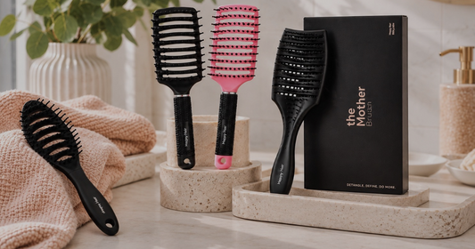 Happy Hair Brush collection in black, pink and purple displayed on a bright bathroom vanity.