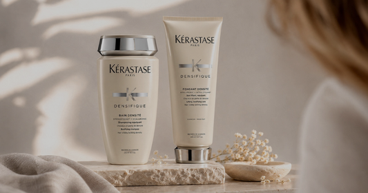 Kérastase Densifique shampoo and conditioner displayed on a stone surface in warm, natural light.